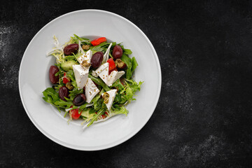 Greek salad on a plate, on a dark background