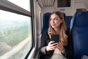 Beautiful woman traveling with train holding smartphone sitting and relaxed