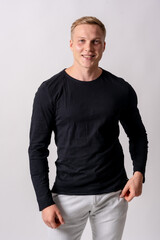 Attractive blond german model with black sweater on a white background, looking at camera smiling