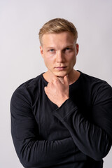 Obraz premium Attractive blond german model in a black sweater on a white background, posed in a pensive fashion