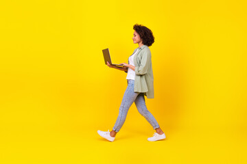 Profielfoto over de volledige lengte van ceo millennial brunette lady go with laptop wear shirt jeans shoes geïsoleerd op gele achtergrond