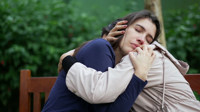 Supportive Friend Consoling Suffering Girl At Park Bench. Depressed Young Woman Embraced By Empathic Companion