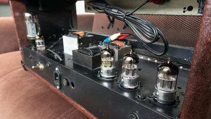 handcrafted brown leather covered amp head in the background 6l6 power lamp 12ax7 sound lamps audio output power inputs and spring loaded reverb tank