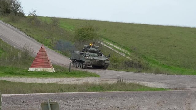 British army Warrior FV510 Fighting Vehicle in action driving on a mud track on a military battle exercise, Wiltshire UK