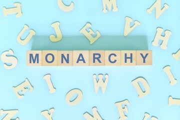 Monarchy government form concept. Wooden blocks typography flat lay in blue background.