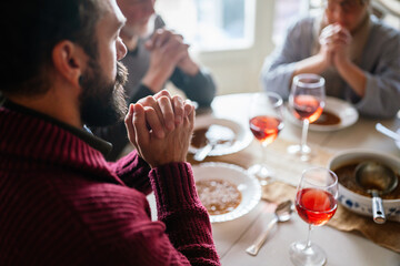 Family and religious concept. Group of multiethnic people with food praying before meal