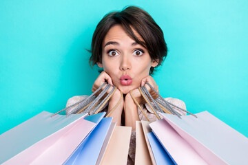 Portrait of impressed charming person pouted lips hands hold bags isolated on turquoise color...