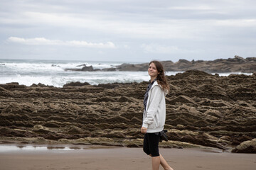 Girl walks on the Itzurun Beach in Zumaia, Basque Country, Spain. Flysh rocks.
