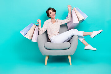 Fototapeta na wymiar Photo of positive adorable fashionista lady stylish trendy clothes outfit sit cozy chair enjoy shopping isolated on cyan color background