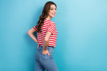 Fototapeta na wymiar Photo of young adorable gorgeous nice pretty cute lady wear red striped t-shirt hands pockets looking back empty space isolated on blue color background