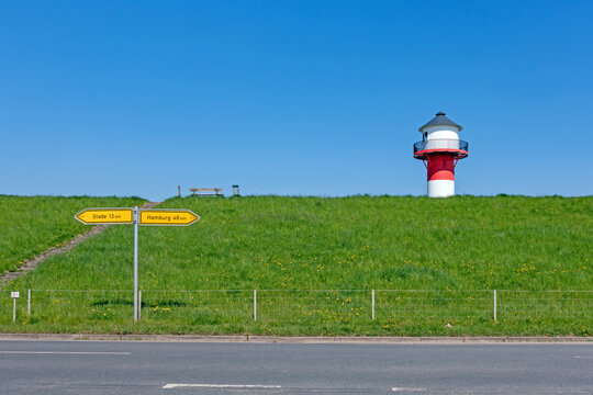 Ein rot-wei&szlig;er Leuchtturm ragt &uuml;ber einen Deich im Alten Land bei L&uuml;he, Deutschland