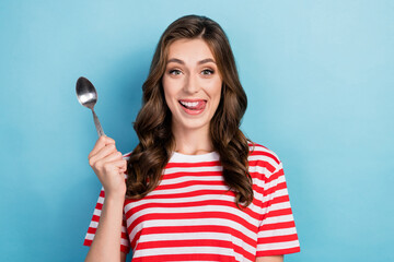Photo of tricky hungry lady wear striped t-shirt licking lips rising spoon isolated blue color background - obrazy, fototapety, plakaty