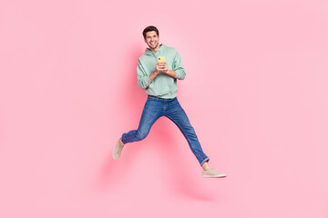 Fototapeta na wymiar Full length photo of overjoyed positive man wear stylish khaki clothes rejoice new cool device telephone isolated on pink color background