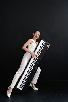 brunette in white plays the synthesizer like a guitar on a black background