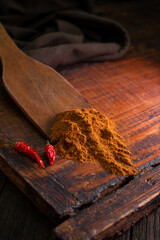 Delicious spicy pepper seasoning with dried red chili peppers on a vintage brown wooden board