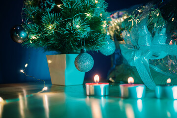 Beautiful turquoise blue-green light on small table Christmas tree with silver baubles and present....
