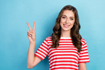 Photo of pretty adorable young lady wear striped clothes smiling showing v-sign isolated blue color background