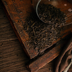 Leaf dried green tea scattered on a wooden board, top view