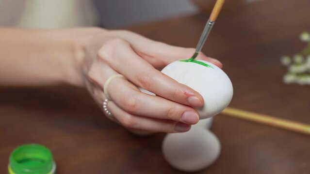 Close-up of a woman's hands painting an easter egg with a paintbrush. Church holiday-Easter