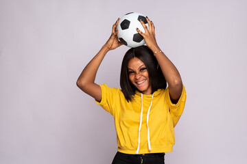 excited young black lady holding a soccer ball