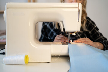 woman sewing clothes while sitting at her workplace in fashion workshop.