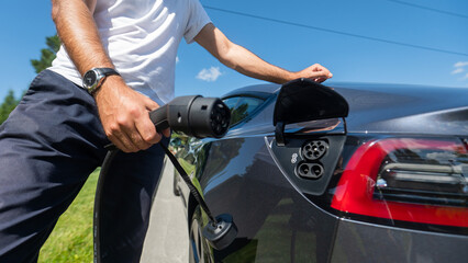 Fototapeta na wymiar Caucasian man connect charger to electric car. 