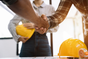 Construction workers, architects and engineers shake hands while working for teamwork and cooperation after completing an agreement in an office facility, successful cooperation concept.