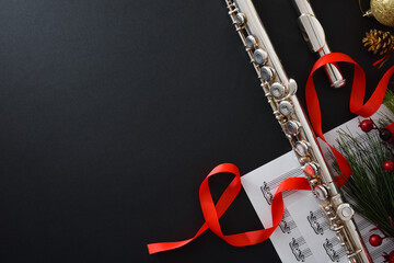 Background with metal flute on black table and Christmas decoration