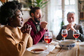 Family and religious concept. Group of multiethnic people with food praying before meal