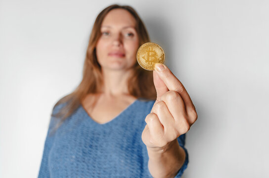 Portrait of woman in casual clothes looking at camera holding bitcoin, future currency, isolated on white background in studio. People lifestyle concept.