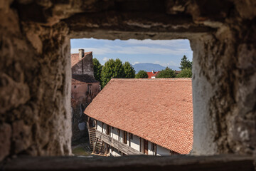 Through square loophole of Prejmer fortified church wall, Transylvanian beautiful panoramic view opens, starting from tiled fortress roof, Brasov, Romania