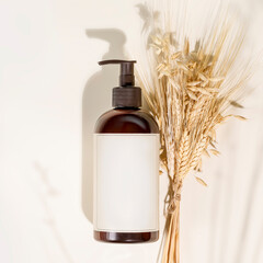Fototapeta premium Dispenser bottle with organic beauty product on a light background with rye and wheat bouquet. Natural beauty product. Mock up of natural washing gel. Flat lay