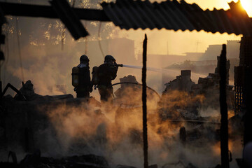 Silhouette of two firefighters working during a fire at a shanty town in Sao Paulo, Brazil.