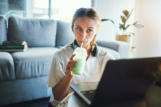 Student, laptop and smoothie for education, digital elearning and research for college in living room. University, studying and school woman, working on email, project or online exam with drink