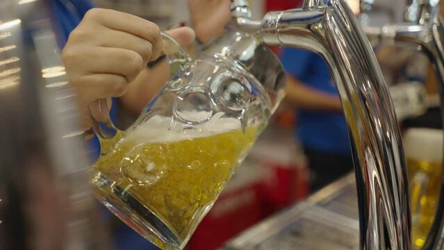 A womans hand refilling a beer mug with a beer puller in Spain