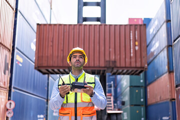 Engineer working in container storage yard fly drone looking location layout prepare to delivery