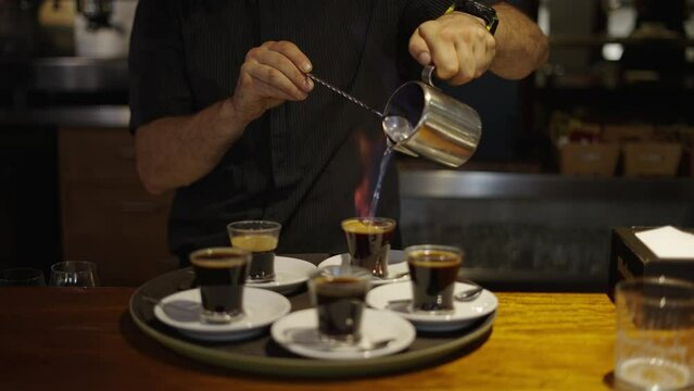 Adult male hands preparing coffee with alcoholic beverage and fire