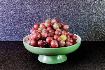 Purple grapes on a black background on a plate