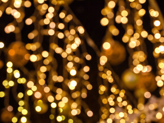 Fototapeta na wymiar Close up of defocused christmas balls and golden garland night street lights. Bokeh garlands background. New Year concept