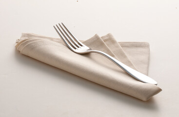 Tenedor sobre servilleta beige de hilo sobre fondo blanco. Fork on beige linen napkin on a white background.