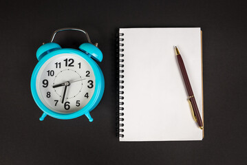 top view photo of blue alarm clock and blank white notepad