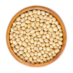 Raw soybeans, in a wooden bowl. Whole and dried seeds of the legume and oilseed Glycine max, also known as soy bean or soya bean. Close-up, from above, isolated, on white background. Macro food photo.