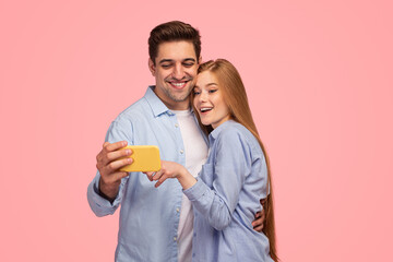 Happy young couple watching video on smartphone