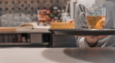Detalle de camarero irreconocible, llevando la bandeja con el té, en la barra del restaurante. - obrazy, fototapety, plakaty