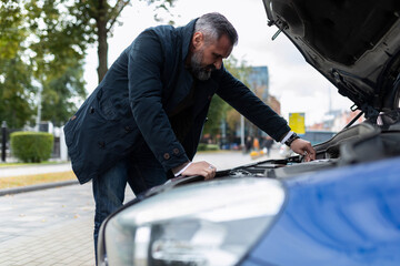 man fixing a broken car in the city