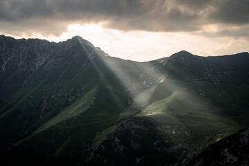 Light rays are shining through the clouds and on the hills of the Orobie Alps, Northern Italy