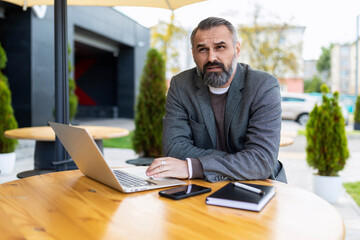 Fototapeta na wymiar adult male businessman with beard working on laptop outside