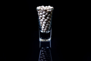 raw white beans in glass jar, wine glass. in bucket. raw white beans on black background. front view raw white beans, dropped from hand, isolated