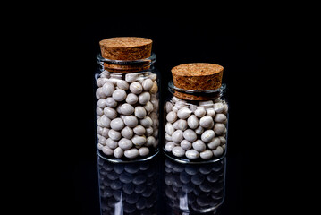 raw white beans in glass jar, wine glass. in bucket. raw white beans on black background. front...