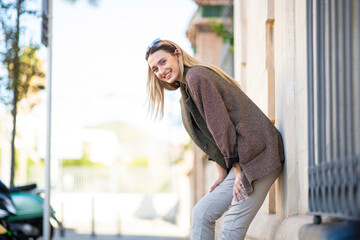 Profile of stylish lady posing outdoors by leaning on wall and bending forward